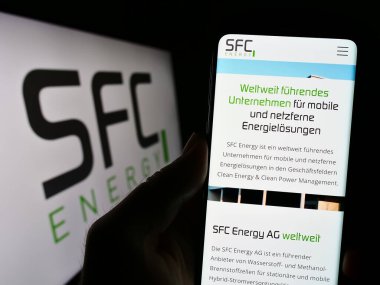 Stuttgart, Almanya - 08-22-2023: Alman firması SFC Energy AG 'nin internet sayfası ile cep telefonu tutan kişi iş logosu önünde ekranda. Telefon ekranının merkezine odaklan.
