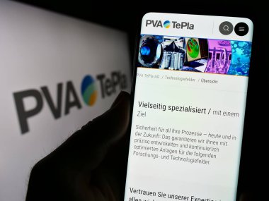Stuttgart, Almanya - 08-22-2023: Alman teknoloji şirketi PVA TePla AG 'nin web sayfası ile akıllı telefon sahibi kişi logonun önünde ekranda. Telefon ekranının merkezine odaklan.