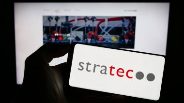 Stuttgart, Almanya - 08-22-2023: Alman tanı firması STRATEC SE 'nin logosuyla cep telefonu sahibi kişi iş sayfasının önünde ekranda. Telefon ekranına odaklan.