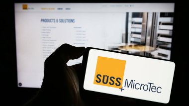 Stuttgart, Almanya - 08-22-2023: Alman teknoloji şirketi Suss Microtec SE 'nin logosunu elinde tutan kişi web sitesinin önünde ekranda. Telefon ekranına odaklan.