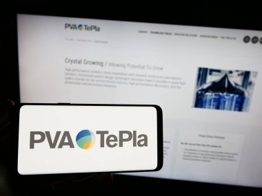 Stuttgart, Almanya - 08-22-2023: Alman teknoloji şirketi PVA TePla AG 'nin logosunu elinde tutan kişi web sitesinin önünde ekranda. Telefon ekranına odaklan.