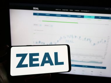 Stuttgart, Almanya - 08-24-2023: Alman piyango şirketi ZEAL Network SE 'nin logosuyla cep telefonu sahibi kişi iş sayfasının önünde ekranda. Telefon ekranına odaklan.