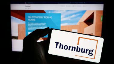 Stuttgart, Almanya - 08-25-2023: Thornburg Yatırım Yönetim Şirketi 'nin logosunu elinde tutan kişi web sitesinin önünde ekranda. Telefon ekranına odaklan.
