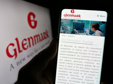 Stuttgart, Almanya - 08-25-2023: Hint Glenmark Pharmaceuticals Limited şirketinin web sayfası ile cep telefonu tutan kişi logolu ekranda. Telefon ekranının merkezine odaklan.