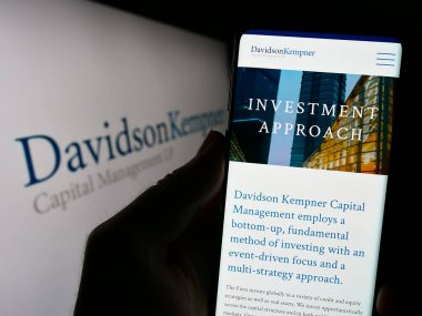 Stuttgart, Almanya - 08-25-2023: ABD 'li Davidson Kempner Capital Management LP şirketinin web sayfası ile cep telefonu tutan kişi logo ile ekranda. Telefon ekranının merkezine odaklan.