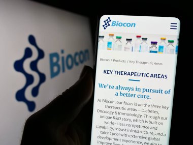 Stuttgart, Almanya - 08-26-2023: Hintli biyofarmasötik şirketi Biocon Limited 'in web sayfası olan akıllı telefonu logolu kişi ekranda. Telefon ekranının merkezine odaklan.