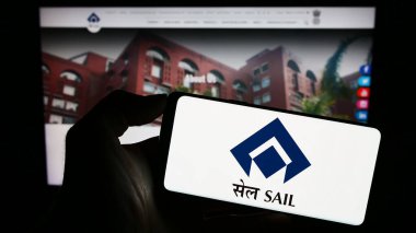 Stuttgart, Germany - 08-26-2023: Person holding cellphone with logo of company Steel Authority of India Limited (SAIL) on screen in front of webpage. Focus on phone display. clipart