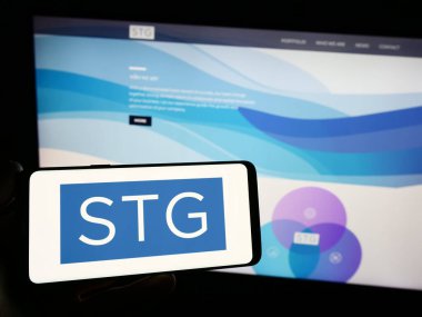 Stuttgart, Almanya - 08-28-2023: ABD 'li özel sermaye şirketi STG Partners LLC' nin logosuna sahip kişi web sitesinin önünde ekranda. Telefon ekranına odaklan.