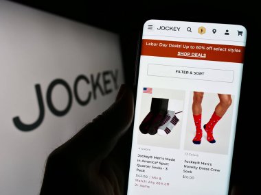 Stuttgart, Almanya - 08-28-2023: ABD 'li giyim şirketi Jockey International Inc.' in internet sayfası ile cep telefonu tutan kişi logolu ekranda. Telefon ekranının merkezine odaklan.
