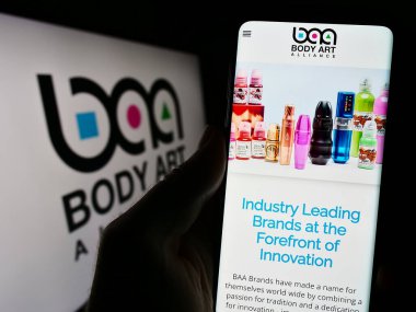 Stuttgart, Almanya - 08-29-2023: ABD 'li kozmetik şirketi Body Art Alliance' ın web sayfası logo önünde cep telefonu tutan kişi. Telefon ekranının merkezine odaklan.