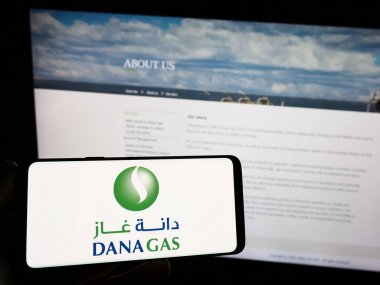 Stuttgart, Almanya - 08-29-2023: Emirati petrol şirketi Dana Gas PJSC 'nin logosunun bulunduğu akıllı telefonu web sitesi önünde ekranda tutan kişi. Telefon ekranına odaklan.