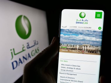 Stuttgart, Almanya - 08-29-2023: Emirati petrol şirketi Dana Gas PJSC 'nin web sitesi ile cep telefonu sahibi kişi logonun önünde ekranda. Telefon ekranının merkezine odaklan.