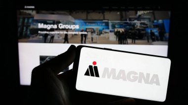 Stuttgart, Almanya - 08-29-2023: Otomotiv şirketi Magna International Inc. 'in logosuna sahip akıllı telefon web sitesinin önünde ekranda. Telefon ekranına odaklan.