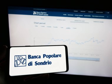 Stuttgart, Almanya - 08-30-2023: Banca Popolare di Sondrio SCpA (BPSO) logosuna sahip cep telefonu sahibi kişi iş sayfasının önünde ekranda. Telefon ekranına odaklan.