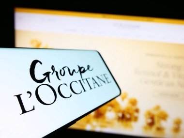 Stuttgart, Germany - 08-30-2023: Smartphone with logo of French cosmetics company Groupe L'Occitane on screen in front of business website. Focus on left of phone display. clipart