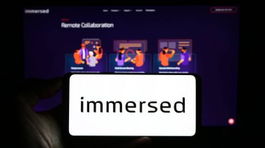 Stuttgart, Almanya - 08-30-2023: ABD 'li sanal gerçeklik şirketi Immersed Inc.' in logosuna sahip cep telefonu sahibi kişi iş sayfasının önünde ekranda. Telefon ekranına odaklan.