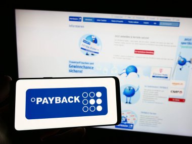 Stuttgart, Almanya - 09-01-2023: Alman sadakat yönetimi şirketi Payback GmbH 'in logosunu elinde tutan kişi web sitesinin önünde ekranda. Telefon ekranına odaklan.