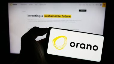 Stuttgart, Germany - 09-01-2023: Person holding mobile phone with logo of French nuclear energy company Orano SA on screen in front of business web page. Focus on phone display. clipart