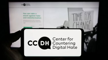 Stuttgart, Almanya - 09-02-2023: Web sayfası önünde ekranda Dijital Nefretle Mücadele Merkezi (CCDH) logosu bulunan kişi. Telefon ekranına odaklan.