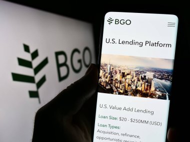 Stuttgart, Almanya - 09-02-2023: Yatırım şirketi BentallGreenOak 'ın (BGO) web sitesi logo önünde cep telefonu tutan kişi. Telefon ekranının merkezine odaklan.
