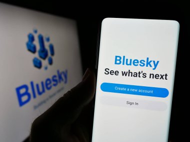 Stuttgart, Almanya - 09-02-2023: Sosyal ağ girişimi Bluesky 'nin web sayfası ile akıllı telefonu olan kişi logo önünde ekranda. Telefon ekranının merkezine odaklan.