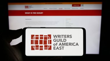 Stuttgart, Almanya - 09-02-2023: Doğu Amerika İşçi Sendikası Yazarları Derneği (WGAE) logosunun bulunduğu cep telefonu web sayfası önünde. Telefon ekranına odaklan.