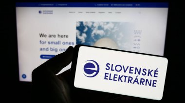 Stuttgart, Almanya - 09-02-2023: Enerji şirketi Slovenske Elektrarne 'ın logosuna sahip akıllı telefon sahibi kişi web sitesinin önünde ekranda. Telefon ekranına odaklan.