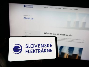 Stuttgart, Almanya - 09-02-2023: Enerji şirketi Slovenske Elektrarne 'ın logosunun bulunduğu cep telefonu sahibi kişi iş sayfasının önünde ekranda görülüyor. Telefon ekranına odaklan.