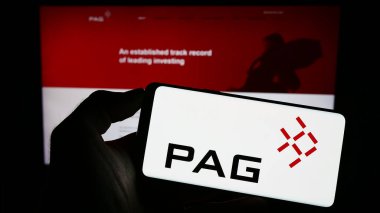 Stuttgart, Almanya - 09-02-2023: Asyalı yatırım şirketi PAG 'nin logosunun bulunduğu cep telefonu sahibi kişi iş sayfasının önünde ekranda. Telefon ekranına odaklan.