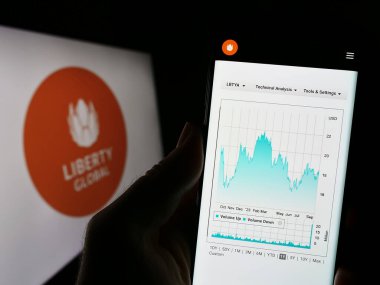 Stuttgart, Almanya - 09-02-2023: Telekomünikasyon şirketi Liberty Global 'in web sayfası ile birlikte logo önünde cep telefonu tutan kişi. Telefon ekranının merkezine odaklan.