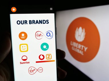 Stuttgart, Almanya - 09-02-2023: Telekomünikasyon şirketi Liberty Global 'in web sayfası ve logosu olan cep telefonu sahibi kişi. Telefon ekranının merkezine odaklan.