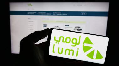 Stuttgart, Almanya - 09-02-2023: Suudi Arabistan araba kiralama şirketi Lumi 'nin logosunu taşıyan cep telefonu sahibi şahıs iş sayfasının önünde ekranda. Telefon ekranına odaklan.