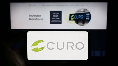 Stuttgart, Almanya - 09-05-2023: ABD 'li finans şirketi CURO Group Holding Corp' un logosunu elinde tutan kişi web sitesinin önünde ekranda. Telefon ekranına odaklan.