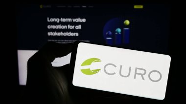 Stuttgart, Germany - 09-05-2023: Person holding cellphone with logo of American financial company CURO Group Holdings Corp. on screen in front of webpage. Focus on phone display. clipart