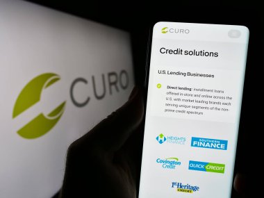 Stuttgart, Almanya - 09-05-2023: ABD 'li finans şirketi CURO Group Holding Corp' un web sitesi ile cep telefonu tutan kişi logolu ekranda. Telefon ekranının merkezine odaklan.