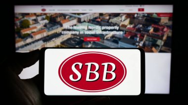 Stuttgart, Almanya - 09-06-2023: Web sitesi önünde Samhallsbyggnadsbolaget i Norden AB (SBB) logosuna sahip akıllı telefon sahibi kişi. Telefon ekranına odaklan.