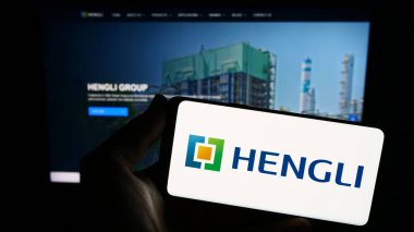 Stuttgart, Almanya - 09-06-2023: İnternet sitesinin önünde ekranda Çinli petrokimya şirketi Hengli Group 'un logosuna sahip akıllı telefonu tutan kişi. Telefon ekranına odaklan.