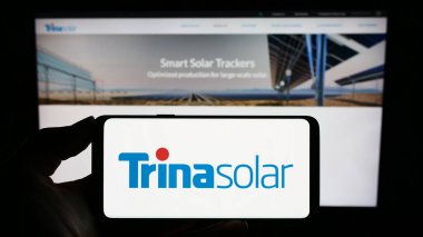 Stuttgart, Almanya - 09-07-2023: Çinli PV şirketi Trina Solar Co. Ltd. nin logosuyla cep telefonu sahibi kişi iş sayfasının önünde ekranda. Telefon ekranına odaklan.
