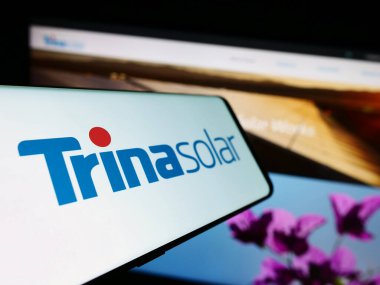 Stuttgart, Almanya - 09-07-2023: Çinli PV şirketi Trina Solar Co. Ltd. nin logosuna sahip akıllı telefon iş sitesinin önünde ekranda. Telefon ekranının merkez soluna odaklan.