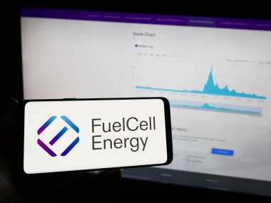 Stuttgart, Almanya - 09-08-2023: Web sayfasının önünde ekranda Amerikan yakıt hücresi şirketi FuelCell Energy Inc. 'in logosunun bulunduğu cep telefonu sahibi kişi. Telefon ekranına odaklan.