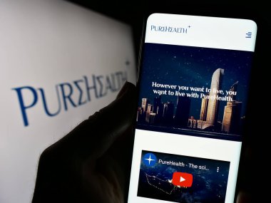 Stuttgart, Almanya - 09-08-2023: Emirati şirketi Pure Health LLLC 'nin (Pure Health LLLC) web sitesi ile cep telefonu tutan kişi logolu ekranda görülüyor. Telefon ekranının merkezine odaklan.