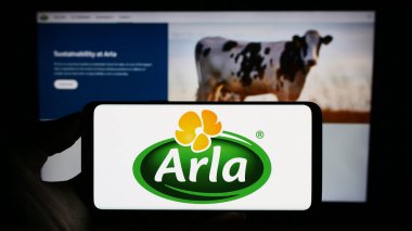 Stuttgart, Almanya - 09-08-2023: İskandinav süt ürünleri şirketi Arla Foods amba 'nın logosunun bulunduğu cep telefonu sahibi kişi iş sayfasının önünde ekranda. Telefon ekranına odaklan.