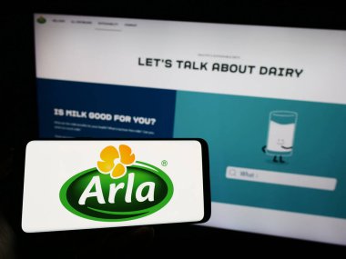 Stuttgart, Almanya - 09-08-2023: İskandinav süt ürünleri şirketi Arla Foods amba 'nın logosuyla cep telefonu sahibi kişi iş sayfasının önünde ekranda. Telefon ekranına odaklan.