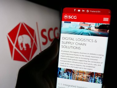 Stuttgart, Almanya - 09-09-2023: The Siam Cement Public Company Limited 'in (SCG) web sayfası logolu cep telefonu tutan kişi. Telefon ekranının merkezine odaklan.