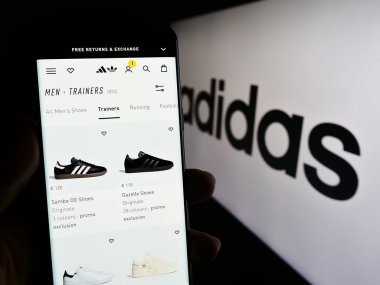 Stuttgart, Almanya - 09-09-2023: Alman giyim ve ayakkabı şirketi Adidas AG 'nin web sayfası bulunan cep telefonu sahibi kişi logolu ekranda. Telefon ekranının merkezine odaklan.