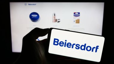 Stuttgart, Almanya - 09-09-2023: Alman tüketici malları şirketi Beiersdorf AG 'nin logosuyla cep telefonu sahibi kişi iş sayfasının önünde ekranda görülüyor. Telefon ekranına odaklan.