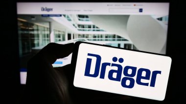 Stuttgart, Almanya - 09-09-2023: Alman Draegerwerk AG Co. KGaA (Drger) şirketinin logosuna sahip cep telefonu sahibi kişi web sayfası önünde ekranda. Telefon ekranına odaklan.