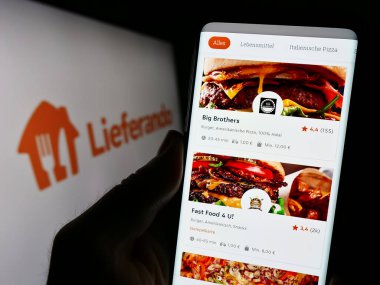 Stuttgart, Almanya - 09-10-2023: Alman gıda dağıtım şirketi Lieferando 'nun internet sayfası ile akıllı telefon taşıyan kişi logonun önünde ekranda. Telefon ekranının merkezine odaklan.