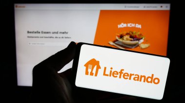Stuttgart, Almanya - 09-10-2023: İnternet sitesinin önünde Alman gıda dağıtım şirketi Lieferando 'nun logosunu taşıyan kişi. Telefon ekranına odaklan.