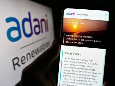 Stuttgart, Almanya - 07-26-2023: Hintli Adani Green Energy Limited şirketinin web sayfası logonun önünde duran kişi. Telefon ekranının merkezine odaklan.